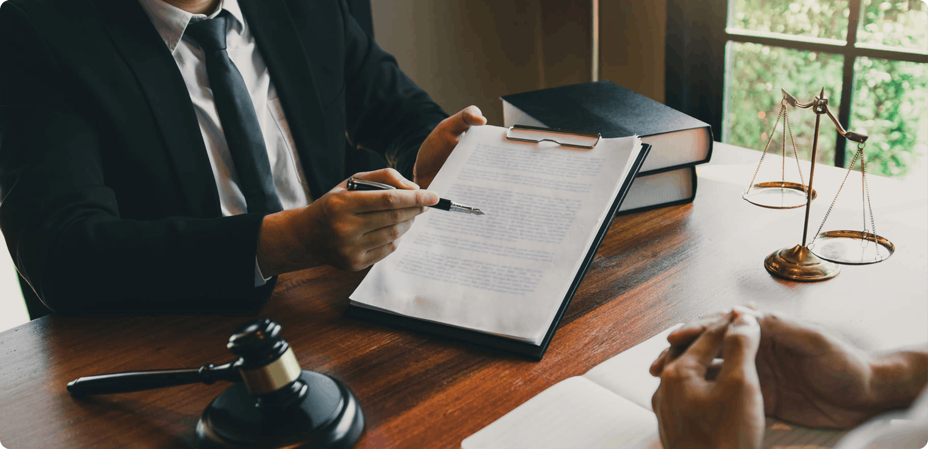 Legal professionals reviewing a document beside law books, scales and a judge's gavel